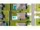 Aerial view of a home's roof and backyard with pool, surrounded by neighboring houses and green lawns at 9785 Pepper Tree Trl, Wildwood, FL 34785