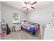 Neutral bedroom featuring carpet floors, window with blinds, a fan, and playful kid-themed decor at 9785 Pepper Tree Trl, Wildwood, FL 34785