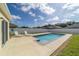 Outdoor pool with two chairs, a white fence, and blue skies in the backyard at 9785 Pepper Tree Trl, Wildwood, FL 34785