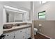 Bright bathroom featuring a large mirror, granite countertop and cabinets, with a window providing natural light at 4219 Magnolia Ave, Leesburg, FL 34748