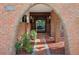 Charming brick archway frames a view into an elegant dining room, accentuated by lush greenery and a tiled walkway at 4219 Magnolia Ave, Leesburg, FL 34748
