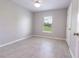 This bedroom features a ceiling fan, a window with blinds, and light gray tile flooring at 10128 County Road 229, Oxford, FL 34484