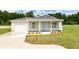 Charming single-story home featuring light siding, blue shutters, a covered front porch, and an attached garage at 10128 County Road 229, Oxford, FL 34484