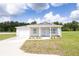 Charming single-story home featuring light blue shutters, a covered porch, and an attached garage at 10128 County Road 229, Oxford, FL 34484