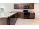 Well-equipped kitchen featuring dark wood cabinetry, stainless steel appliances, and tile flooring throughout at 10128 County Road 229, Oxford, FL 34484
