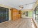 Light-filled sunroom showcasing wood-look flooring, built-in cabinets, and access to the outdoors at 10161 Sw 87Th Ter, Ocala, FL 34481
