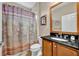 Well-maintained bathroom with wood cabinetry, dark granite countertop, and shower with curtain at 109 Falling Acorn Ave, Groveland, FL 34736