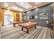 This upscale game room has two covered billiard tables and wall-mounted TVs over a striped rug at 109 Falling Acorn Ave, Groveland, FL 34736
