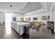 This open-plan room features a massive kitchen island, adjacent seating, a piano, and elegant dark wood floors at 109 Falling Acorn Ave, Groveland, FL 34736