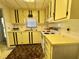 A cozy kitchen with yellow cabinetry, white appliances, and a window above the sink at 112 Caladium St, Leesburg, FL 34748
