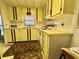 Compact kitchen features yellow cabinets, a white stove, and a double sink beneath a window at 112 Caladium St, Leesburg, FL 34748