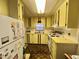 A cozy kitchen shows yellow cabinetry, white appliances, and wood flooring at 112 Caladium St, Leesburg, FL 34748