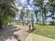 View of the backyard with a wooden deck, lush green grass, and mature trees overlooking the water at 11401 Cypress Dr, Clermont, FL 34711