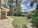 The backyard of the home features a lush lawn, mature trees, and a brick walkway at 11401 Cypress Dr, Clermont, FL 34711