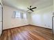 Bright bedroom with hardwood floors, white walls, ceiling fan, and natural light from the windows at 11401 Cypress Dr, Clermont, FL 34711