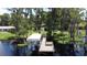 Aerial view of the waterfront property featuring a private dock with a covered boat lift on a serene lake at 11401 Cypress Dr, Clermont, FL 34711