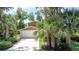 House with a two-car garage, driveway, and lush tropical landscaping, including palm trees at 11401 Cypress Dr, Clermont, FL 34711