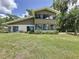 A charming two-story home with large windows and beautiful landscaping is surrounded by a sprawling green lawn at 11401 Cypress Dr, Clermont, FL 34711