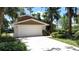 Charming home featuring a two-car garage and a long driveway surrounded by lush tropical landscaping at 11401 Cypress Dr, Clermont, FL 34711