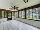 Bright sunroom with tile flooring, wood trim, a ceiling fan, and beautiful views of the yard and lake at 11401 Cypress Dr, Clermont, FL 34711