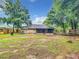 View of a large backyard with mature trees, patio and screened in porch at 12181 Se 87Th Ct, Belleview, FL 34420
