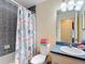 This bathroom features a shower with curtain, commode with stacked towels, and vanity with storage at 12181 Se 87Th Ct, Belleview, FL 34420