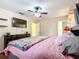 Primary bedroom featuring a TV, en suite bathroom, pink pillows, and overhead fan at 12181 Se 87Th Ct, Belleview, FL 34420