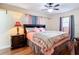 Bedroom with a wood-look floor, decorative lamp, and a large bed under a ceiling fan at 12181 Se 87Th Ct, Belleview, FL 34420