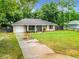 Exterior view featuring a well-manicured lawn, driveway, and partial fence surrounding the charming single story home and attached garage at 12181 Se 87Th Ct, Belleview, FL 34420