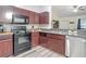 Well-equipped kitchen featuring dark cabinets, stainless steel appliances, stone countertops, and updated flooring at 12181 Se 87Th Ct, Belleview, FL 34420