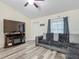 Comfortable living room with new flooring, a dark gray sectional sofa, ceiling fan, and a corner TV cabinet with a built in fireplace at 12181 Se 87Th Ct, Belleview, FL 34420
