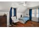 Bright bedroom with hardwood floors, white walls, chair, and blue patterned bed at 126 E Beach St, Groveland, FL 34736