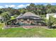 An aerial view showing a screened-in pool and outdoor living area with lush landscaping and green grass at 13 Hickory Head Hammock, The Villages, FL 32159