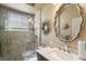 Well-lit bathroom showcasing a walk-in shower, large round mirror, stylish vanity, and neutral color palette at 13 Hickory Head Hammock, The Villages, FL 32159