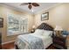 Cozy bedroom featuring a paisley patterned bedspread, wood floors, large window, and a decorative ceiling fan at 13 Hickory Head Hammock, The Villages, FL 32159