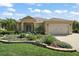 Charming single-story home with a well-kept lawn, colorful landscaping, and an attached two-car garage at 13 Hickory Head Hammock, The Villages, FL 32159