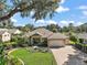 Landscaped home on a large lot featuring a manicured lawn and mature trees that provide shade and beauty at 13 Hickory Head Hammock, The Villages, FL 32159