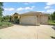 Well-maintained home featuring a large three car attached garage and lush front yard landscaping at 13 Hickory Head Hammock, The Villages, FL 32159