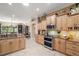 Bright kitchen featuring wood cabinets, tile flooring, granite countertops, and stainless steel appliances at 13 Hickory Head Hammock, The Villages, FL 32159