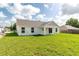 Expansive backyard featuring green grass and an exterior view of the covered back patio at 13334 Sw 107Th St, Dunnellon, FL 34432