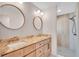 Bright bathroom featuring double vanity with stylish faucets, round mirrors, and a walk-in shower at 13334 Sw 107Th St, Dunnellon, FL 34432