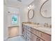 Bright bathroom featuring double vanity with stylish faucets, round mirrors, and adjacent room at 13334 Sw 107Th St, Dunnellon, FL 34432