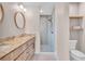 Bright bathroom featuring double vanity with stylish faucets, round mirrors, and a walk-in shower with shelves at 13334 Sw 107Th St, Dunnellon, FL 34432
