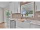 Close-up of a farmhouse sink and stainless steel dishwasher beneath a window with backyard views at 13334 Sw 107Th St, Dunnellon, FL 34432
