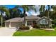 Beautiful single-story home with a two-car garage, complemented by palm trees and colorful landscaping at 1335 Eureka Mill Run, The Villages, FL 32162