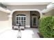 Inviting front porch featuring comfortable seating and decorative pineapple, framed by lush greenery and an arched entryway at 1335 Eureka Mill Run, The Villages, FL 32162