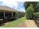 A well-maintained side yard with gravel, grass, landscaping, and partial view of the screened-in back porch at 1335 Eureka Mill Run, The Villages, FL 32162