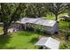 Aerial view of home, showcasing its lush lawn, metal roof, and outdoor seating area with mature tree coverage at 1436 Spring Lake Rd, Fruitland Park, FL 34731