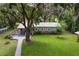 Inviting home boasts lush lawn, stone accents, and a metal roof, nestled under mature trees with Spanish moss at 1436 Spring Lake Rd, Fruitland Park, FL 34731