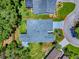 An aerial view shows the layout of a house with an elongated roof and mature trees on a large corner lot at 17037 Se 76Th Creekside Cir, The Villages, FL 32162